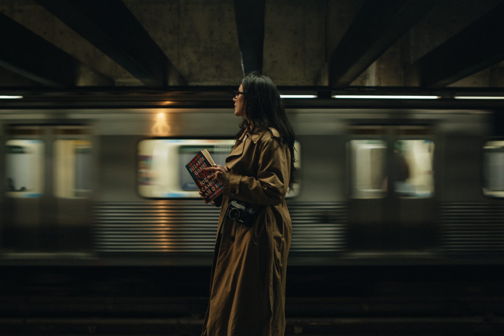 Mulher em plataforma de metrô com trem em movimento